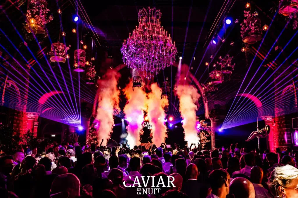 Atmosphere at an exclusive lingerie party — large hall with chandelier, light show and audience