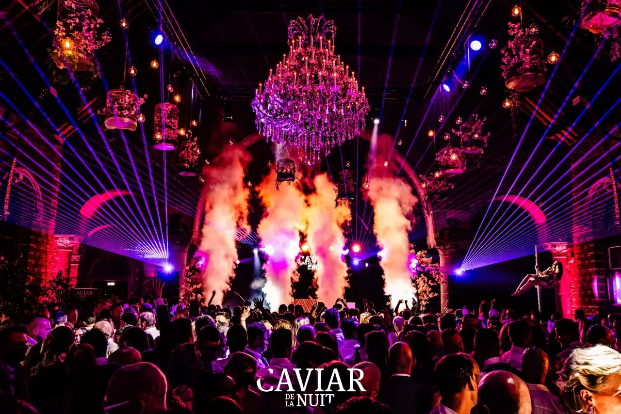Atmosphere at an exclusive lingerie party — large hall with chandelier, light show and audience